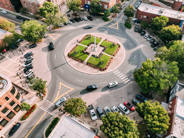 Aerial view of a town roundabout with a central monument, green lawn, and surrounding streets